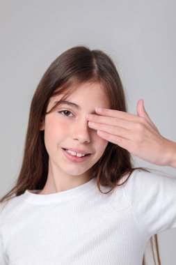 Siyah taytlı uzun saçlı güzel bir genç kızın portresi ve beyaz arka planda bir fotoğraf stüdyosunun kapağı. Farklı duygular. Duygusal bir çekim. Modellik. Fotoğraf mankeni. Fotoğraf oturumu.