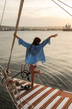 Yazın gün batımında bir yatta güzel, mutlu bir genç kız. Duygusal bir fotoğraf. Fotoşop. Modellik. Fotoğraf mankeni. Yaşam biçimi