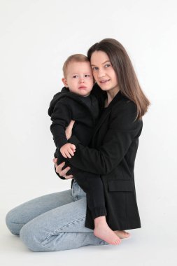 Anne ve küçük oğlu siyah ceketli, beyaz arka planda fotoğraf stüdyosunda. Annelik. Anneler Günü