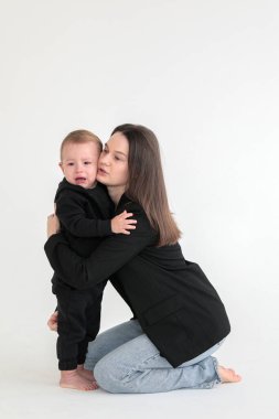 Anne ve küçük oğlu siyah ceketli, beyaz arka planda fotoğraf stüdyosunda. Annelik. Anneler Günü
