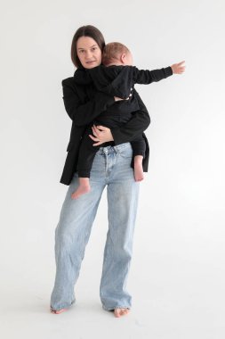 Anne ve küçük oğlu siyah ceketli, beyaz arka planda fotoğraf stüdyosunda. Annelik. Anneler Günü