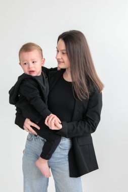 Anne ve küçük oğlu siyah ceketli, beyaz arka planda fotoğraf stüdyosunda. Annelik. Anneler Günü