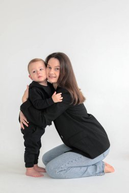 Anne ve küçük oğlu siyah ceketli, beyaz arka planda fotoğraf stüdyosunda. Annelik. Anneler Günü