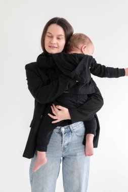 Anne ve küçük oğlu siyah ceketli, beyaz arka planda fotoğraf stüdyosunda. Annelik. Anneler Günü