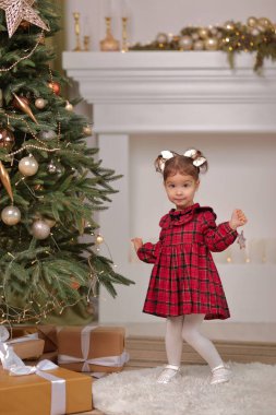 Noel ağacının yanında beyaz elbiseli küçük kız.