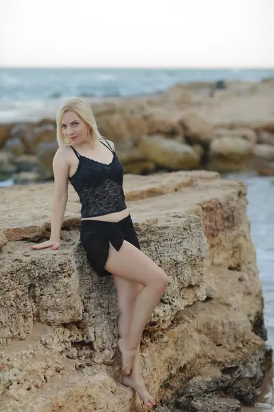 Deniz kenarında siyah mayo ve siyah mayo giyen genç bir kadın.