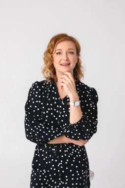 Aydınlık arka planda şık giyinmiş güzel genç bir kadın.