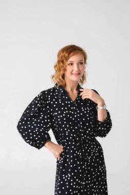 Açık gri arka planda şık giyinmiş güzel genç bir kadın.