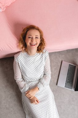 Pembe pijamalı bir yatakta oturan kadın.