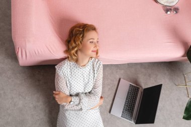 Pembe elbiseli kız ve yatağında dizüstü bilgisayar..