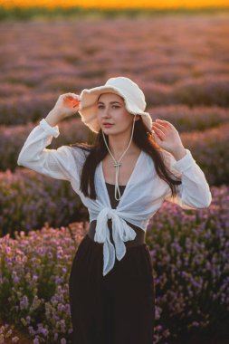 Bir buket kır çiçeğiyle şapkalı genç kız