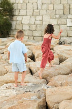 Kayalıklarda iki çocuk elleriyle oynuyor.