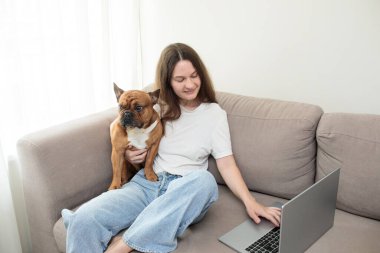 Kadın ve köpek evde dizüstü bilgisayar kullanıyorlar.