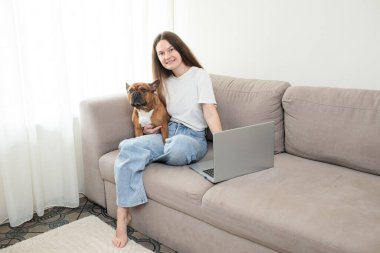 Oturma odasında köpeği olan genç bir kadın.