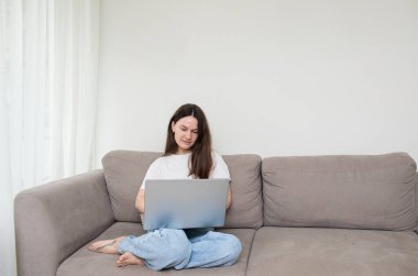 Evde dizüstü bilgisayarda çalışan genç bir kadın.