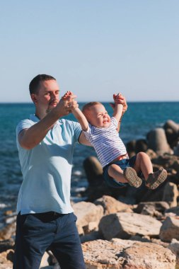 Mutlu baba ve oğul kumsalda oynayıp oynuyorlar. Yazın denizde.