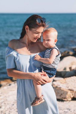 Anne ve oğlu deniz kıyısında yürüyorlar. yüksek kaliteli fotoğraf. Yazın sahilde denizde.