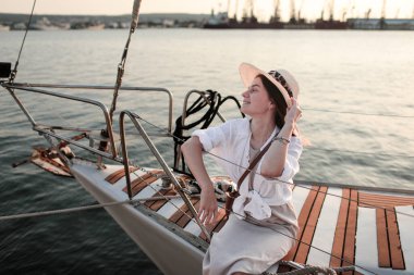 Beyaz gömlekli ve şapkalı güzel bir kız yazın denizde bir yatta..