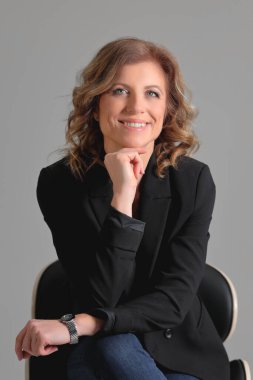 Gri arka planda bir fotoğraf stüdyosunda ceketli güzel bir kadın. İş fotoğrafı çekimi. Portre. İş için. İş kadınıyım. Pozisyon.