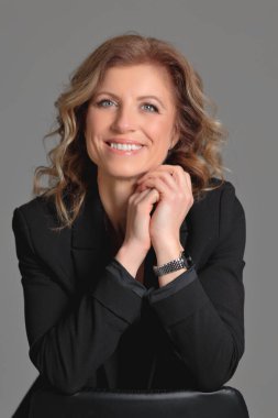 Gri arka planda bir fotoğraf stüdyosunda ceketli güzel bir kadın. İş fotoğrafı çekimi. Portre. İş için. İş kadınıyım. Pozisyon.