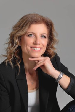 Gri arka planda bir fotoğraf stüdyosunda ceketli güzel bir kadın. İş fotoğrafı çekimi. Portre. İş için. İş kadınıyım. Pozisyon.