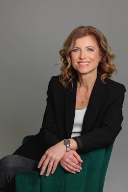 Gri arka planda bir fotoğraf stüdyosunda ceketli güzel bir kadın. İş fotoğrafı çekimi. Portre. İş için. İş kadınıyım. Pozisyon.