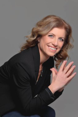 Gri arka planda bir fotoğraf stüdyosunda ceketli güzel bir kadın. İş fotoğrafı çekimi. Portre. İş için. İş kadınıyım. Pozisyon.