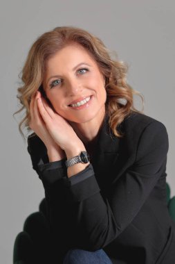 Gri arka planda bir fotoğraf stüdyosunda ceketli güzel bir kadın. İş fotoğrafı çekimi. Portre. İş için. İş kadınıyım. Pozisyon.