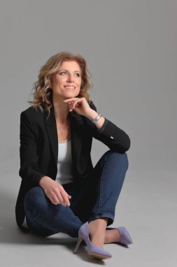 Gri arka planda bir fotoğraf stüdyosunda ceketli güzel bir kadın. İş fotoğrafı çekimi. Portre. İş için. İş kadınıyım. Pozisyon.