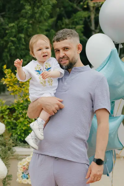 Bebek yazın parkta babasının kollarında oturur.