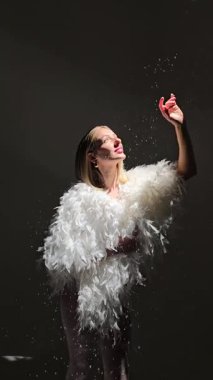 Fotoğraf stüdyosunda beyaz tüylü bir ceket giyen güzel sarışın kız. Modellik. Fotoğraf mankeni. Pozisyon