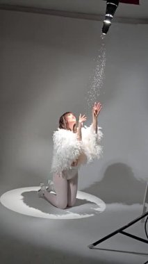 Fotoğraf stüdyosunda siyah saçlı, beyaz tüylü güzel bir kız.