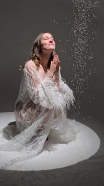 Bir fotoğraf stüdyosundaki beyaz bir pignoirin içinde genç ve güzel bir esmer. Modellik. Fotoğraf mankeni. Pozisyon