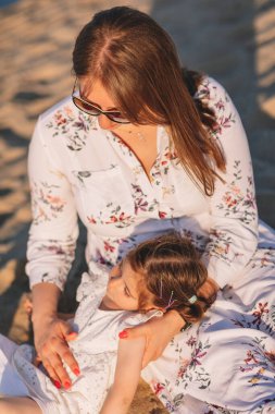 Anne yazın deniz sahilinde kızıyla oynar. Anneler Günü. Annelik