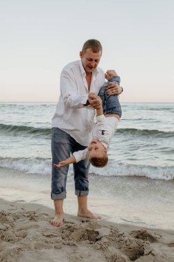 Mutlu baba ve oğul yazın kumsalda oynuyorlar.
