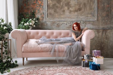 Kızıl saçlı, uzun gri elbiseli güzel bir kız.