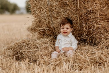 Küçük bir çocuk samanlıkta oturuyor.