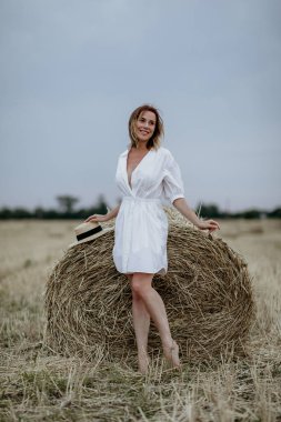Samanlıkların arasında kısa beyaz elbiseli güzel bir genç kız.