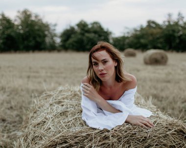 Samanlıkların arasında kısa beyaz elbiseli güzel bir genç kız.