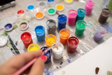 El fırçayla, kavanozlar da masa üzerine çizim yapmak için çok renkli boyayla.