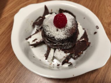 Üzerine pudra şekeri ve ahududu serpilmiş çikolatalı pasta.