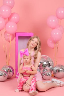 Bir fotoğraf stüdyosunda pembe arka planda iki kız kardeş.