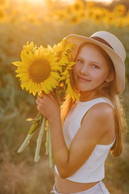 Şapkalı bir kızın portresi, elinde bir ayçiçeği, yüzüne yakın.