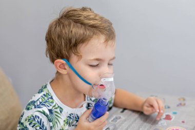 Küçük sarışın çocuk üç-dört yıl bir Nebulizatör ile tedavi edilir, öksürük. Küçük çocuk bir Nebulizatör kullanarak tedavi solunum yapar.
