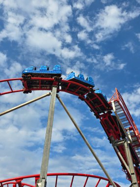 Eğlence parkı. Mavi gökyüzüne ve güzel bulutlara karşı hız treni
