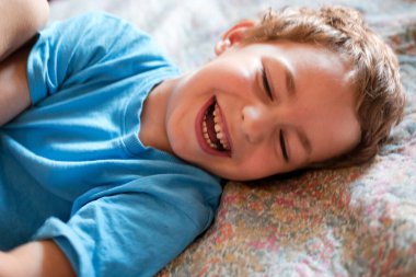 Mavi tişörtlü gülümseyen küçük bir çocuğun portresi.