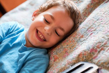 Mavi tişörtlü gülümseyen küçük bir çocuğun portresi.