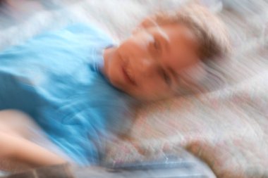 Mavi tişörtlü gülümseyen küçük bir çocuğun portresi.