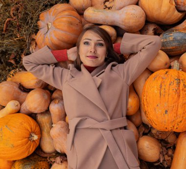 Güzel genç kız sonbaharda bir balkabağının üzerine uzanır. Cadılar Bayramı