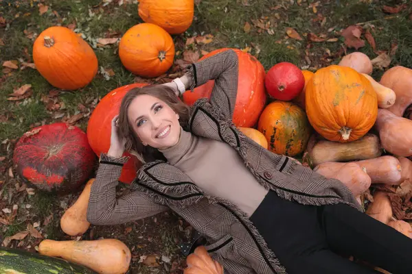 Güzel mutlu kız sonbaharda balkabağının üzerine uzanır. Cadılar Bayramı